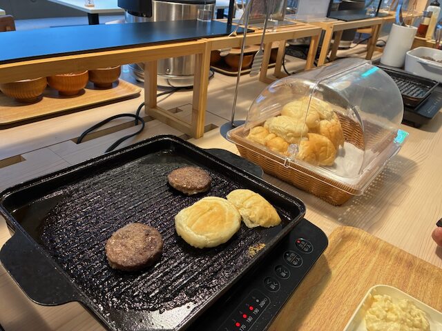 朝食で焼いているあか牛バーガーのハンバーグとバンズ